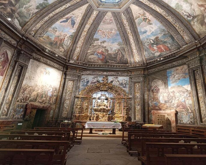 An ornate church interior with frescoes, a central altar, and rows of pews. 4