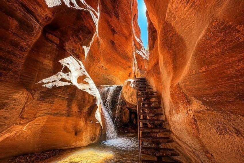 A narrow canyon with a wooden staircase descending into a stream. 1