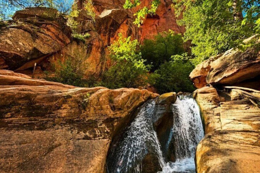 A waterfall cascading over large rocks surrounded by greenery. 5