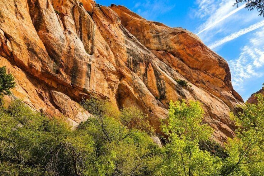 A large red rock formation with green trees in the foreground. 4