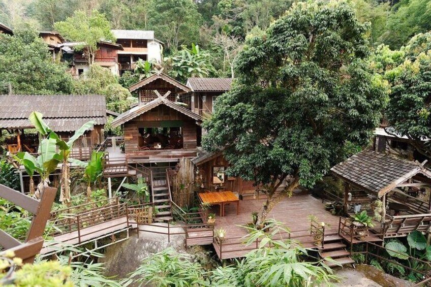 Wooden houses surrounded by lush greenery and a steep hill. 3