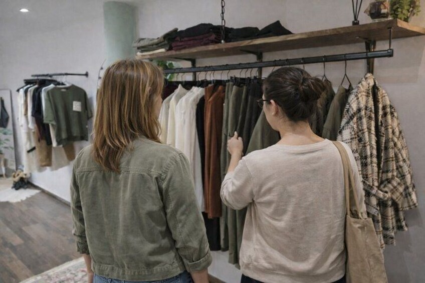 Two people examining clothing on a rack in a retail store. 3