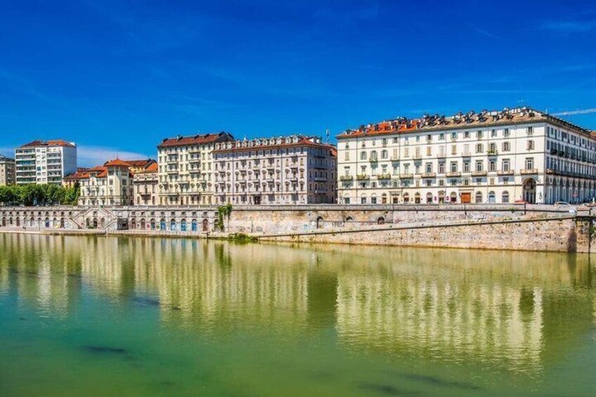 A river with buildings reflecting on the water, a clear sky, and a stone bridge. 4