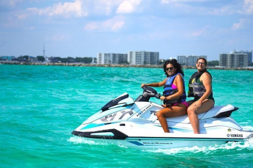 Two people on a Yamaha WaveRunner jet ski in turquoise waters with buildings in the background. 5