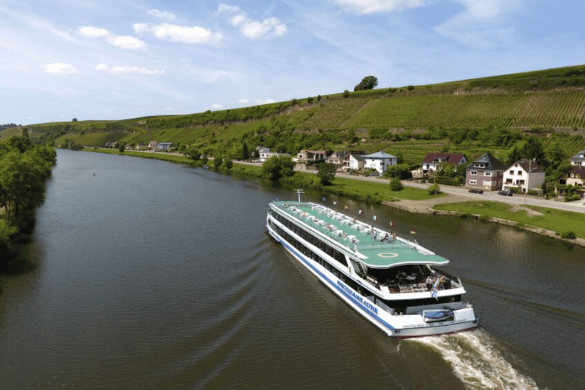 A river cruise ship traveling along a river with houses and greenery on the banks. 3