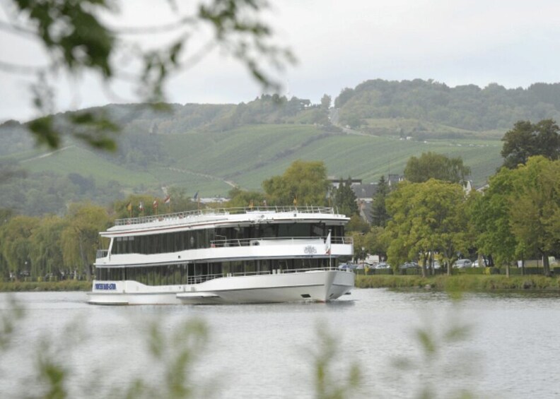 A large white riverboat on calm waters with green hills in the background. 5