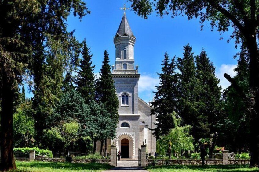 A church with a tall tower, surrounded by trees and a well-maintained lawn. 3