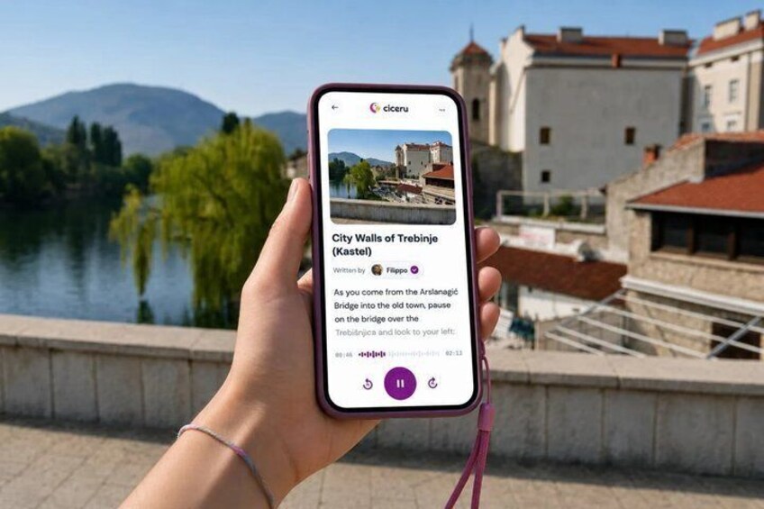 A hand holding a smartphone displaying a location guide for City Walls of Trebinje (Kastel). 1