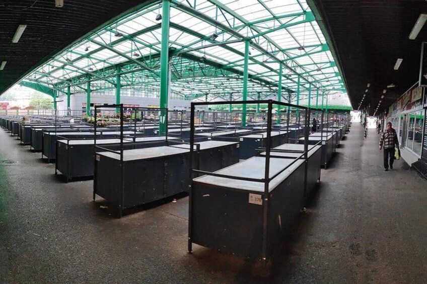 A covered market with rows of black display tables. 2