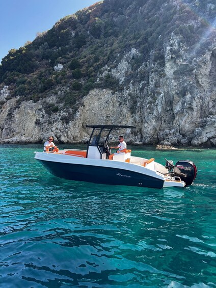 A boat on turquoise water with rocky cliffs in the background. 2