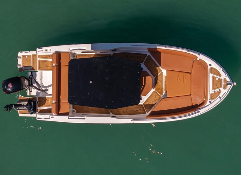 A small motorboat with a cabin, a black deck, and an orange seating area. 3
