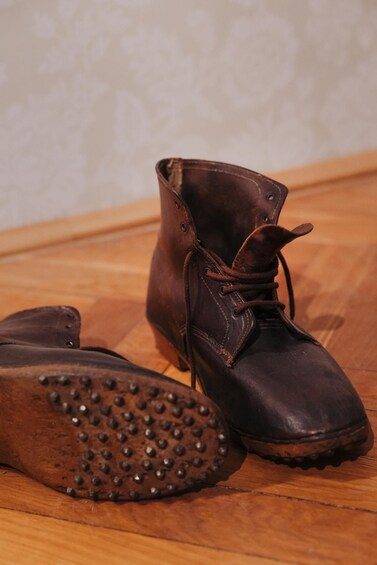 A pair of brown leather boots with studded soles on a wooden floor. 4