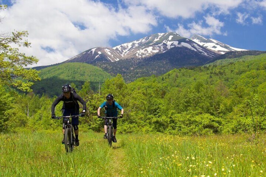 Two cyclists on a trail with a mountain in the background. 1