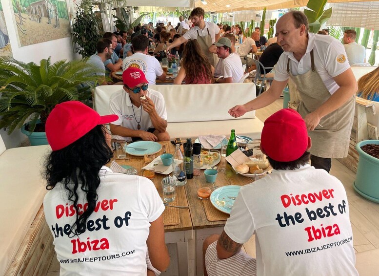 A group of people dining at an outdoor restaurant with a tropical setting. 4