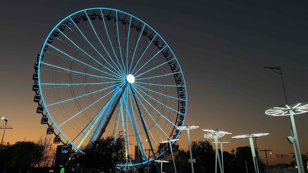 A large Ferris wheel with blue lights against a dusk sky. 5