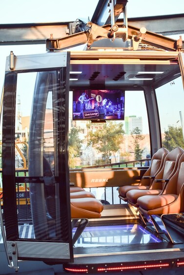 A cable car interior with leather seats and a mounted television screen displaying a live event. 3