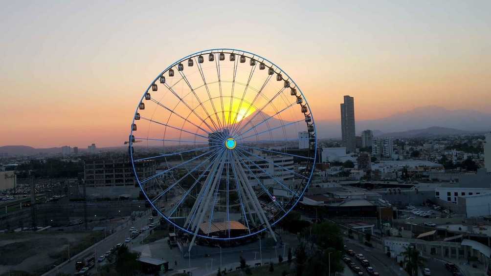 A large Ferris wheel with a sunset in the background. 1