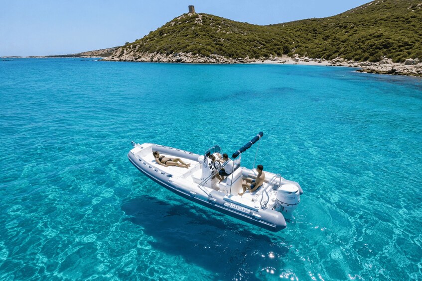 A boat on clear turquoise water with a rocky island and a tower in the background. 3