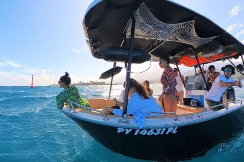 A boat with people on board, a clear sky, and a red buoy in the distance. 1