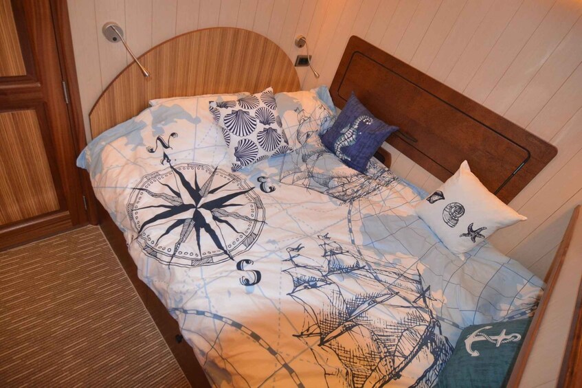A bed with a nautical-themed bedspread, including a compass and ships. 1