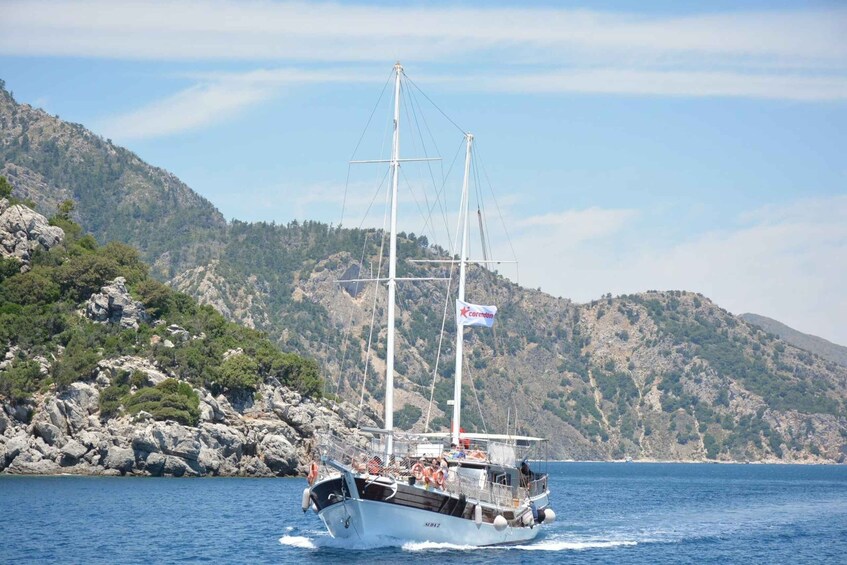 A sailing boat with a flag, navigating near rocky coastlines and hills. 5