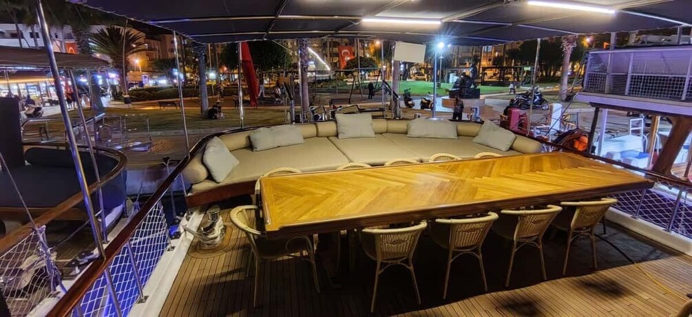 A wooden bar table with chairs on a boat deck at night. 4