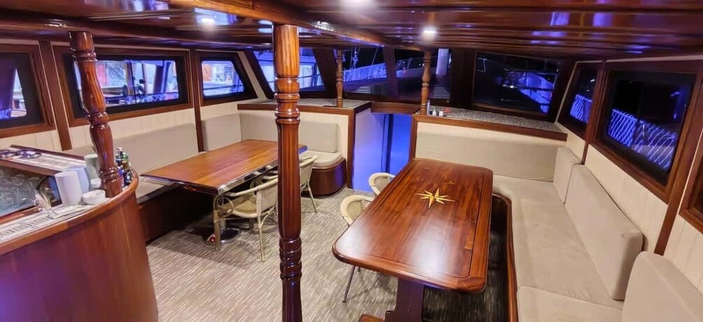 A boat interior with a wooden table, cushioned seating, and multiple screens displaying navigation. 3