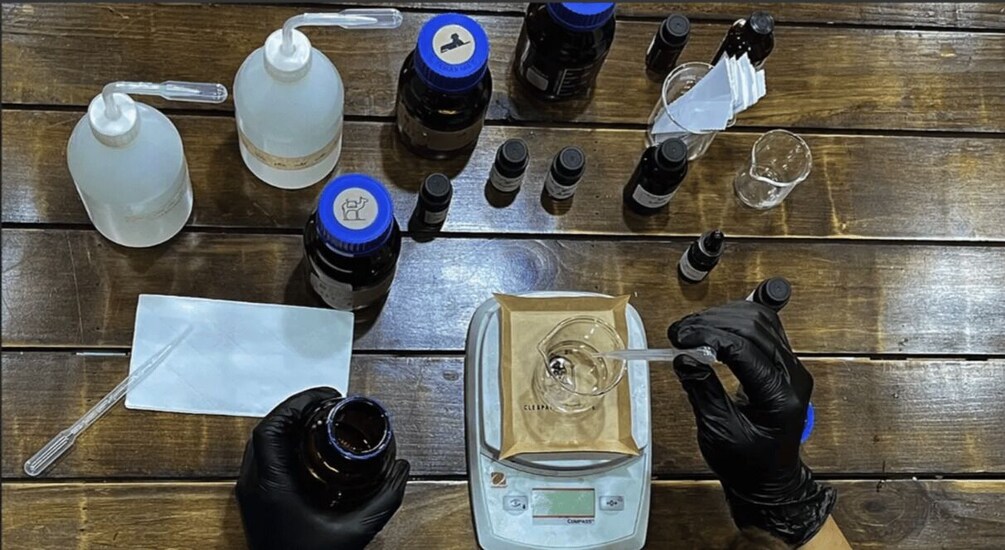A wooden table with various lab equipment, including bottles, a pipette, and a scale. 5