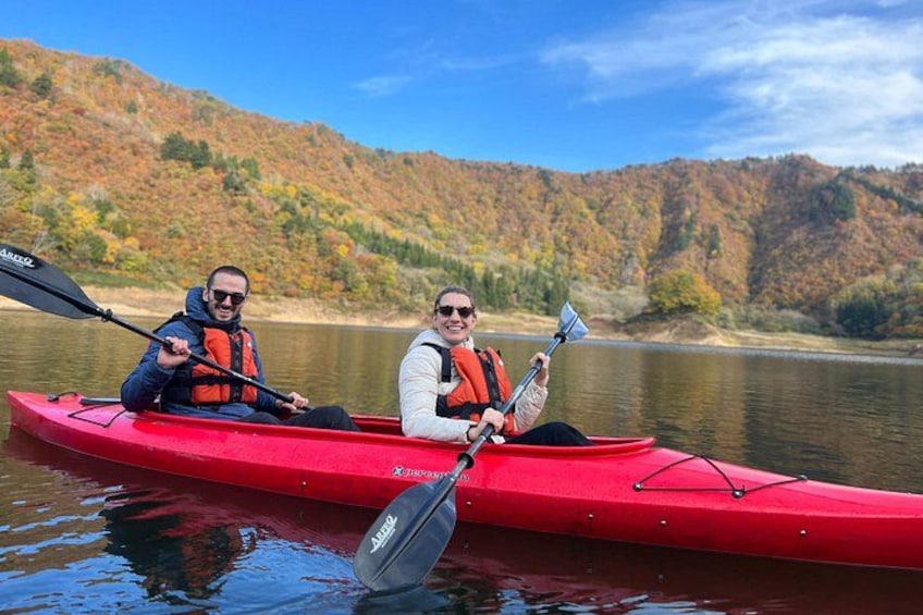 Two people kayaking on a calm river surrounded by autumn-colored hills. 4