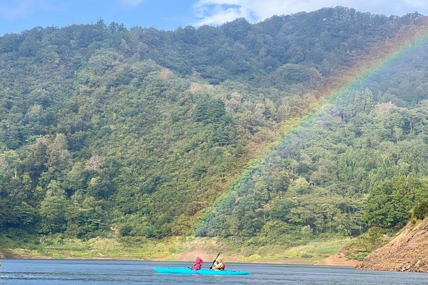 A kayaker on a river with a rainbow in the background. 5