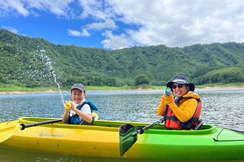 Two people kayaking on a river with a forested mountain in the background. 5