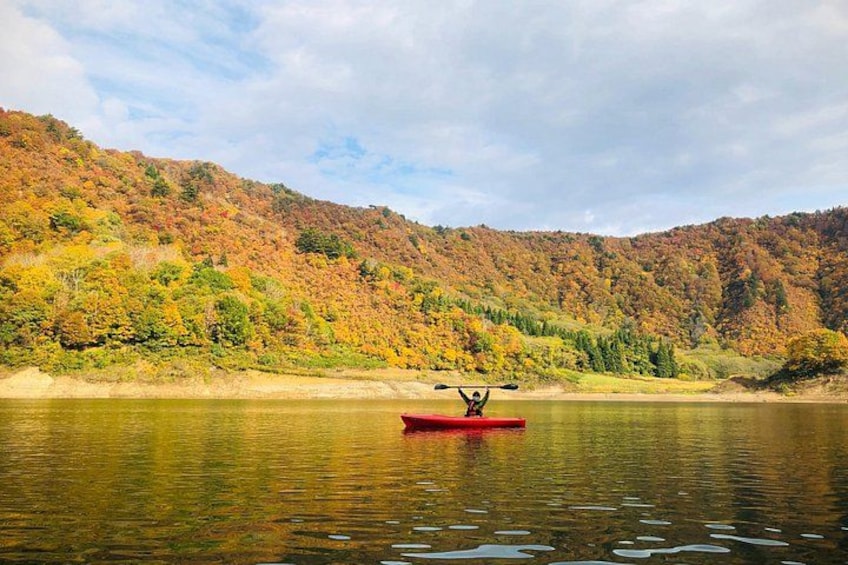 A red canoe on a calm river with autumn-colored trees in the background. 3