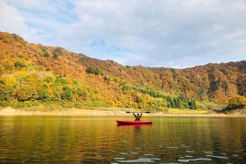 A red canoe on calm water with a hilly forested landscape in the background. 3