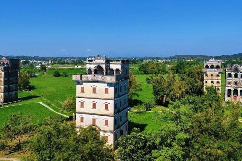 A historical building complex with multiple structures, surrounded by lush greenery and a clear sky. 5
