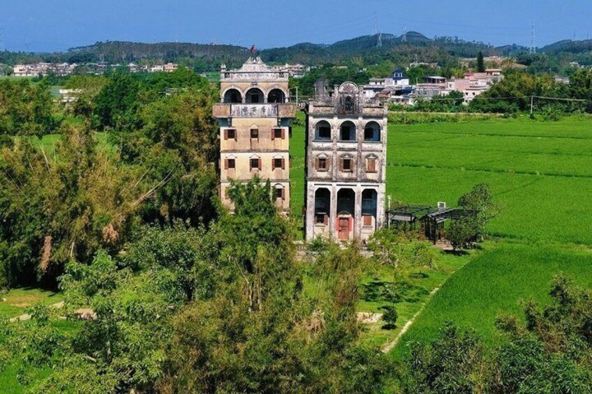 A historic tower with arched windows and a dome, surrounded by lush greenery and fields. 4