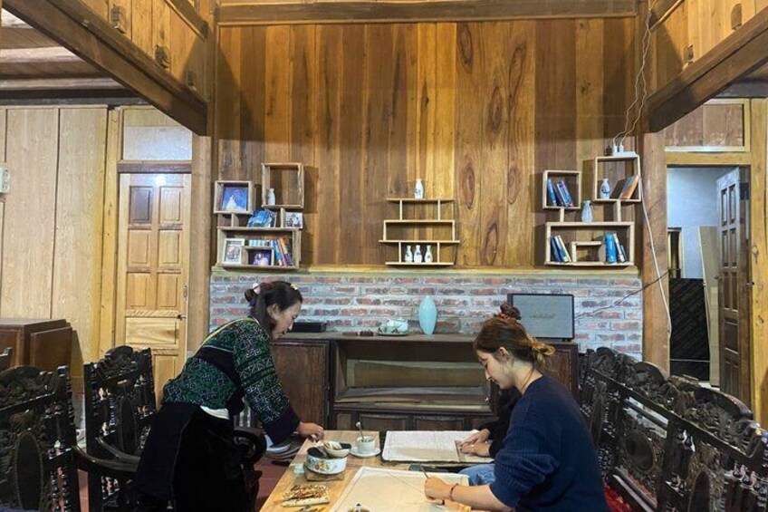 A rustic wooden interior with a brick fireplace, shelves with books and decorative items, and a dining table with chairs. 5
