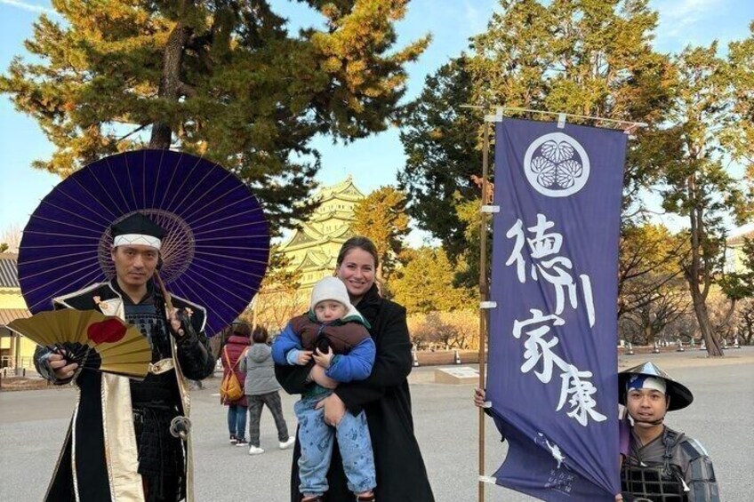 A person in traditional attire holding a fan, a child, and a banner with Japanese characters. 4