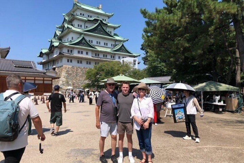 A group of people standing in front of a traditional Japanese castle with a large, multi-tiered structure. 5