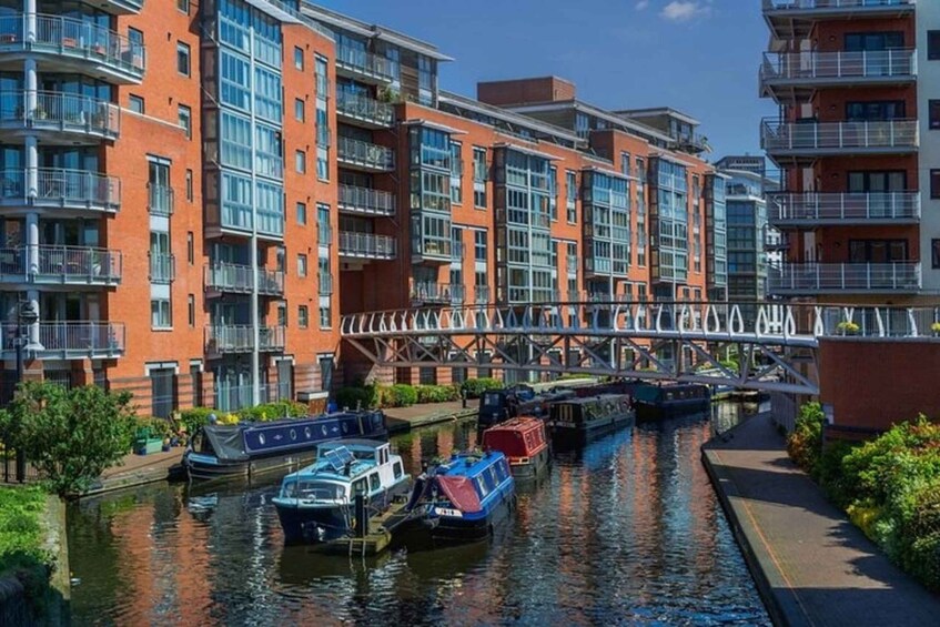 A canal with boats, red brick buildings, and a pedestrian bridge. 4