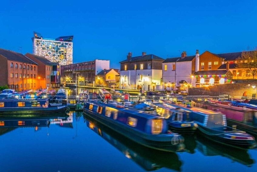 A marina at dusk with boats docked, buildings, and a distinctive modern structure in the background. 5
