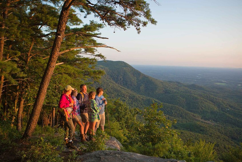 A group of hikers on a mountain trail with a view of a valley. 1