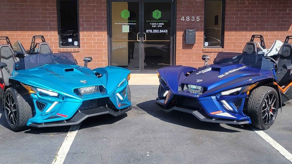 Two sports cars parked in front of a building with a brick facade and a glass door. 3