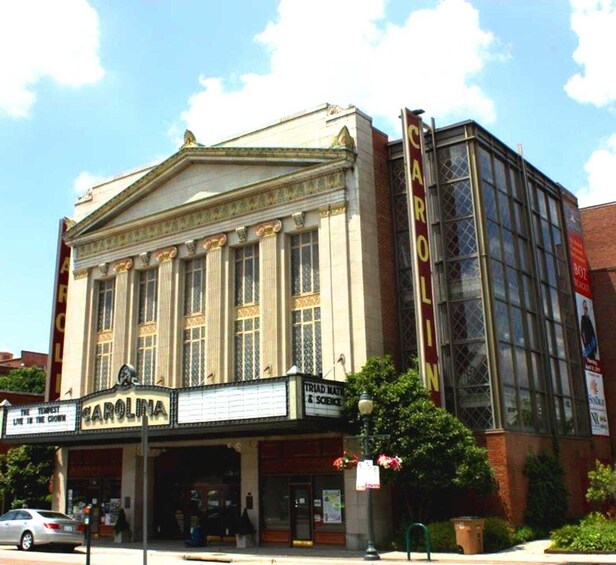 A historic theater with 'CAROLINA' signage, large windows, and a classic architectural design. 1