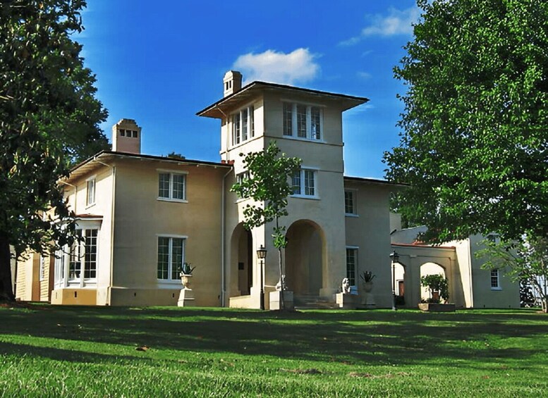 A large, historic building with a central tower, arched windows, and a well-maintained lawn. 3