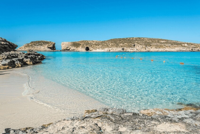 A clear blue sea, rocky coastline, and a sandy beach. 4