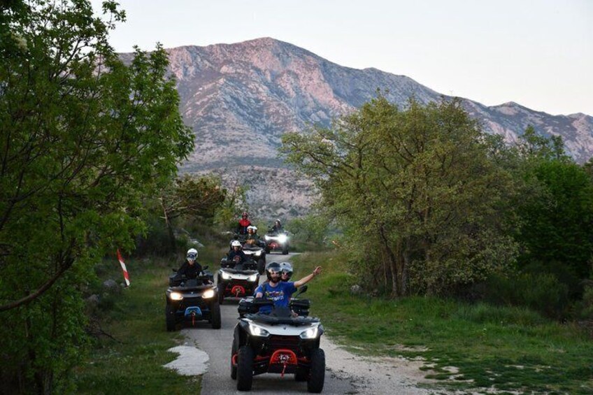 A group of quad bikes on a narrow path with mountains in the background. 5