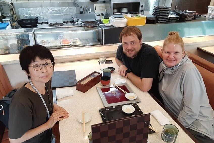 Three people seated at a table in a restaurant with various dishes and utensils. 3