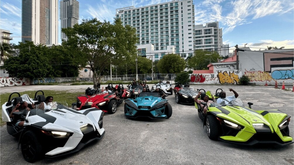 A group of people in go-karts in an urban setting with tall buildings and graffiti in the background. 1