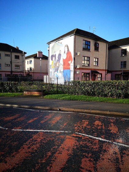 A building with a large mural of people, a road with red markings, and a clear blue sky. 5
