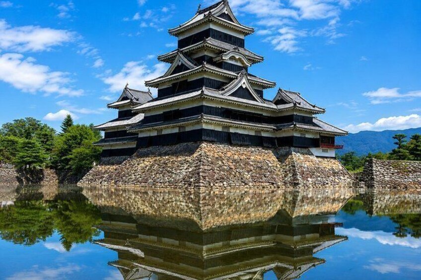 A traditional Japanese castle with multiple tiers, surrounded by a moat and reflecting in the water. 2